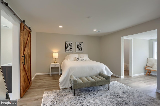 bedroom with light hardwood / wood-style flooring and a barn door