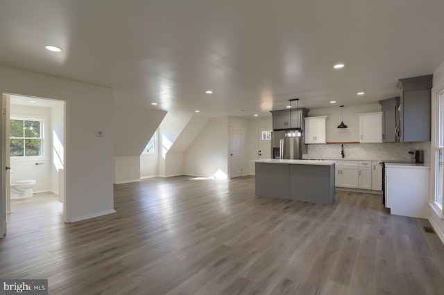 kitchen with gray cabinetry, pendant lighting, a kitchen island, and stainless steel refrigerator with ice dispenser