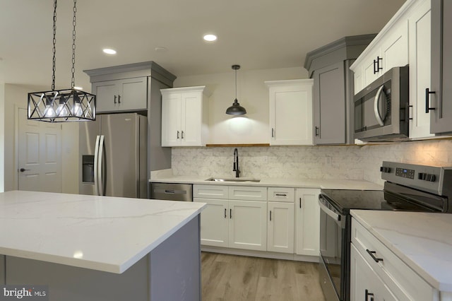 kitchen featuring light stone counters, stainless steel appliances, sink, and hanging light fixtures