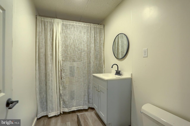 bathroom with toilet, hardwood / wood-style floors, curtained shower, and vanity