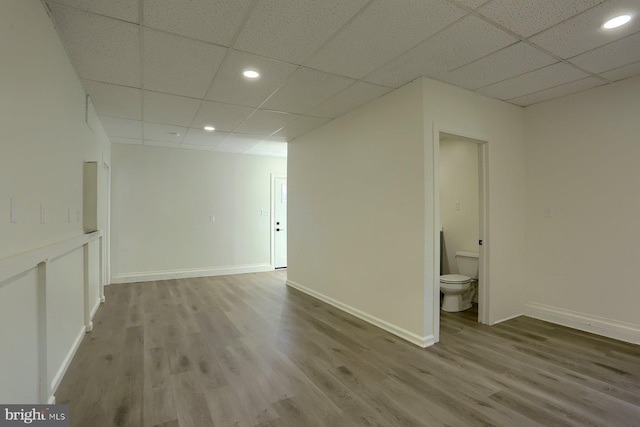 spare room featuring a drop ceiling and hardwood / wood-style flooring