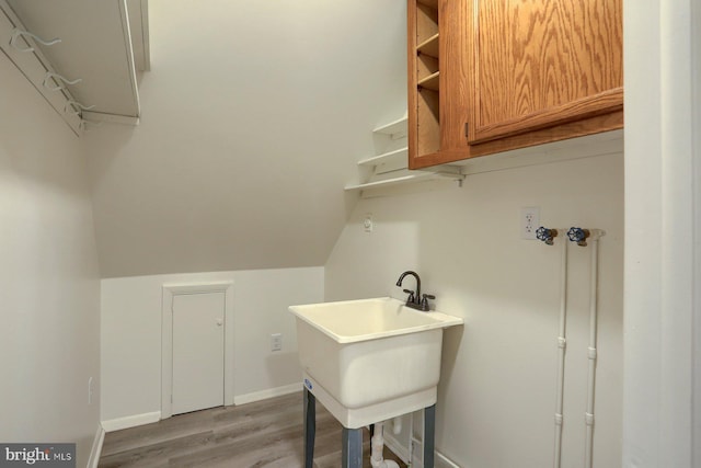 laundry area with light hardwood / wood-style floors and sink