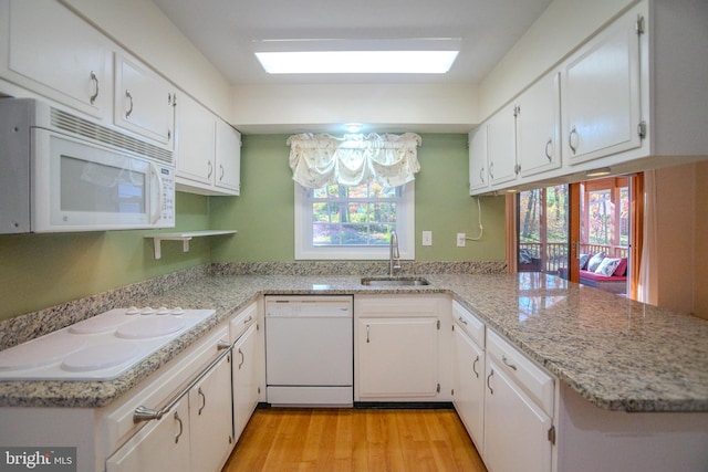 kitchen with white cabinetry, kitchen peninsula, white appliances, and sink