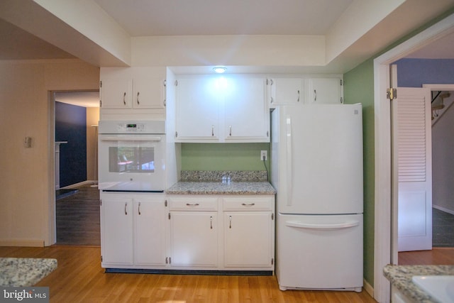 kitchen with light stone countertops, white appliances, white cabinetry, and light wood-type flooring