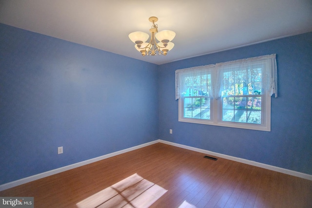 empty room featuring hardwood / wood-style flooring and a chandelier