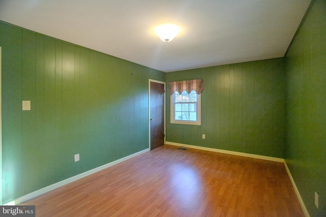 spare room featuring wood walls and hardwood / wood-style flooring