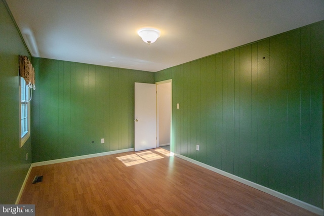 spare room with hardwood / wood-style floors and wooden walls