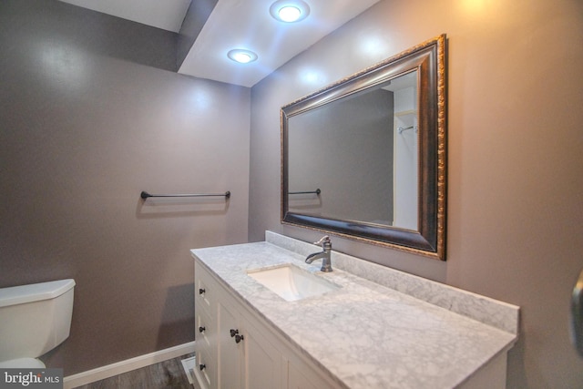 bathroom with toilet, vanity, and hardwood / wood-style flooring