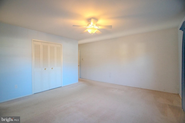 unfurnished bedroom featuring light carpet, ceiling fan, and a closet