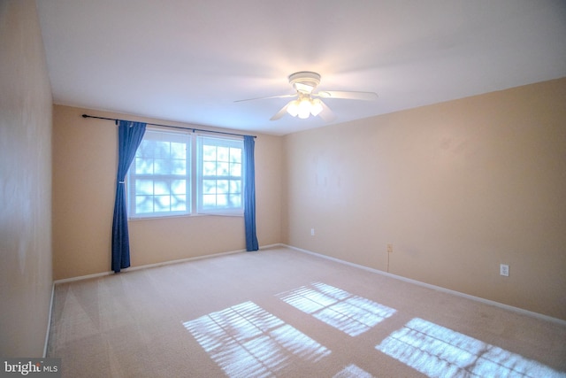 carpeted spare room featuring ceiling fan