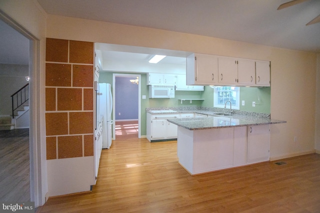 kitchen featuring white cabinetry, sink, kitchen peninsula, white appliances, and light hardwood / wood-style flooring