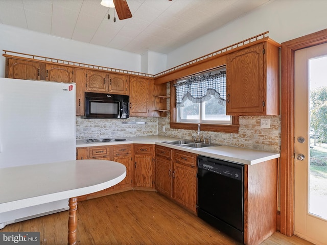 kitchen featuring sink, black appliances, tasteful backsplash, light wood-type flooring, and ceiling fan