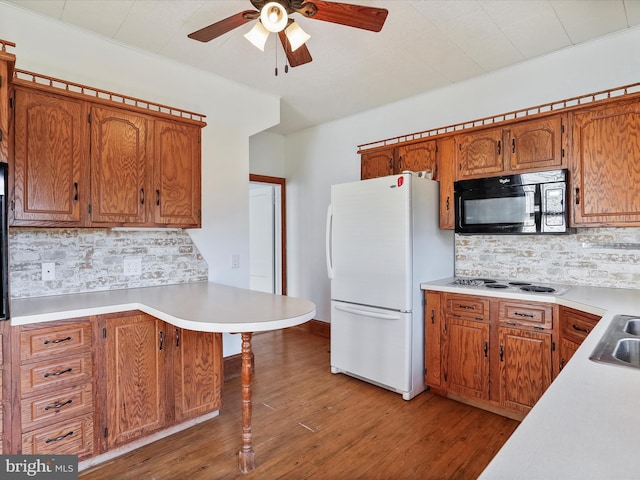 kitchen featuring kitchen peninsula, tasteful backsplash, light wood-type flooring, sink, and white appliances