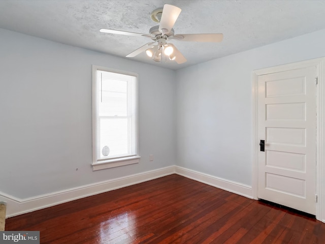 empty room featuring dark wood-type flooring, ceiling fan, and a textured ceiling