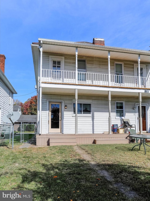 rear view of property with a lawn and a balcony