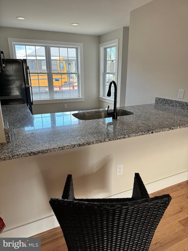 kitchen with black refrigerator, wood-type flooring, sink, and a wealth of natural light