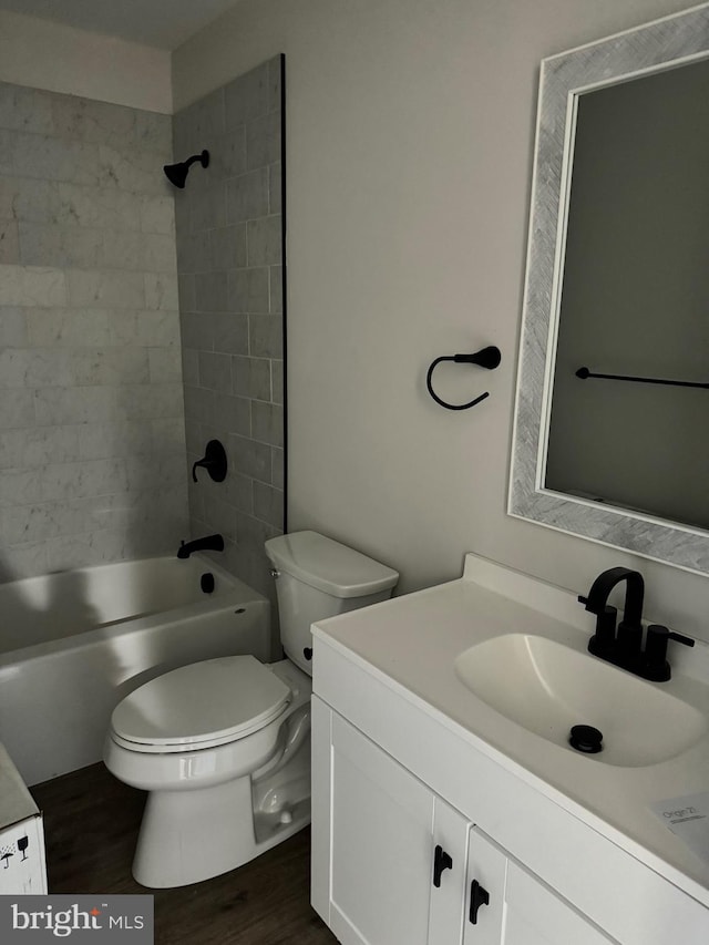 full bathroom featuring hardwood / wood-style floors, tiled shower / bath combo, toilet, and vanity