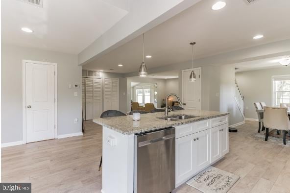 kitchen with hanging light fixtures, white cabinetry, a kitchen island with sink, dishwasher, and sink