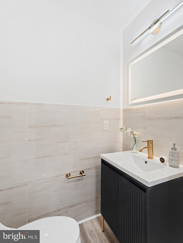 bathroom with vanity, toilet, wood-type flooring, and tile walls