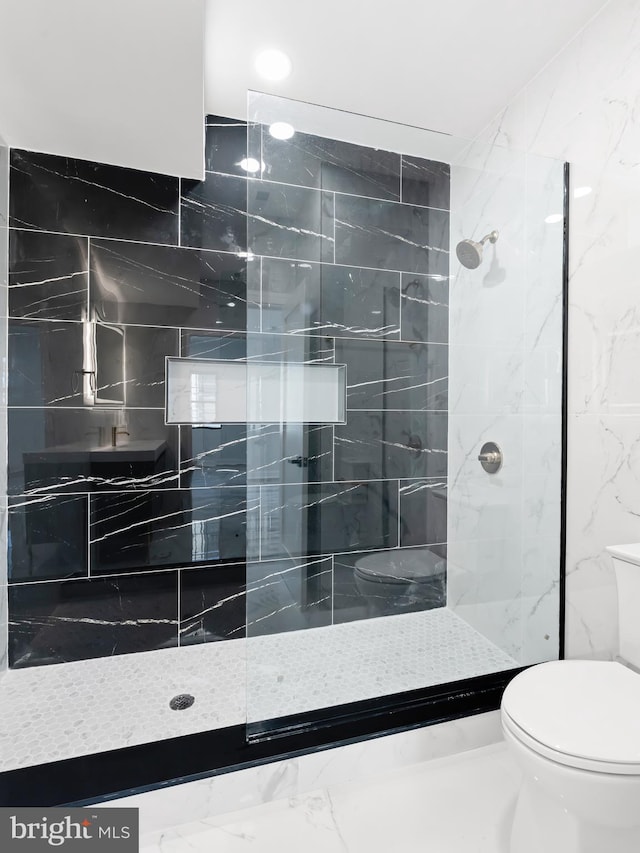 bathroom with tile walls, a tile shower, and toilet