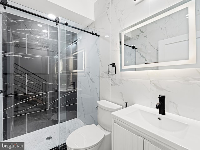 bathroom featuring tile walls, vanity, a shower with shower door, and toilet