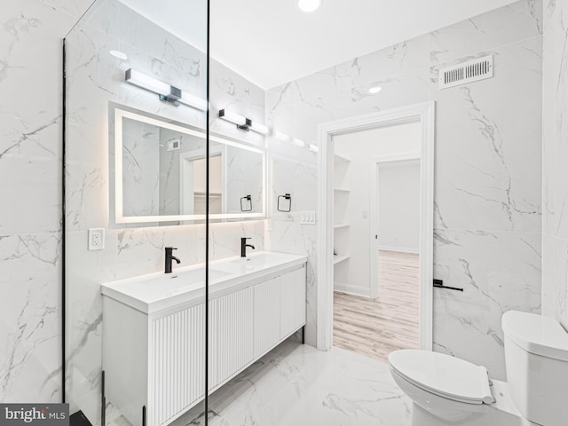 bathroom featuring toilet, vanity, and tile walls