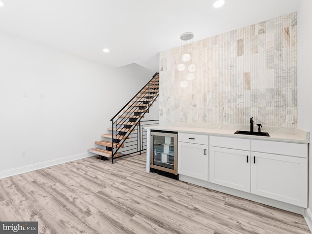 bar with sink, white cabinetry, light wood-type flooring, and beverage cooler