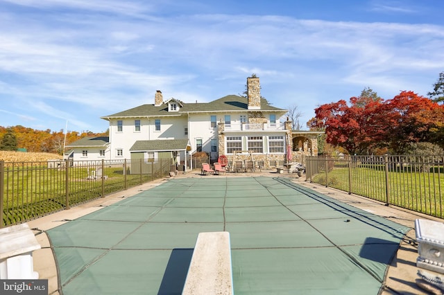 back of house featuring a patio area, a covered pool, and a yard