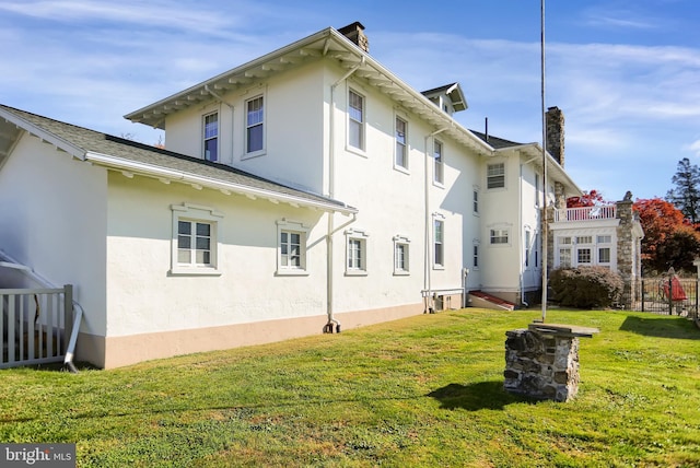 rear view of property with a balcony and a lawn