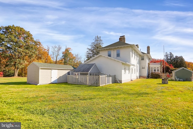 back of property with a storage unit and a yard