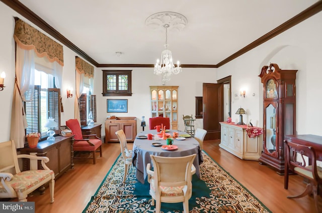 dining area featuring light hardwood / wood-style floors, crown molding, and a notable chandelier