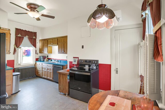 kitchen with a sink, stainless steel appliances, brown cabinetry, a ceiling fan, and radiator heating unit