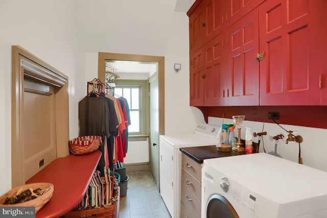 washroom with baseboards, light tile patterned floors, cabinet space, and washer and clothes dryer