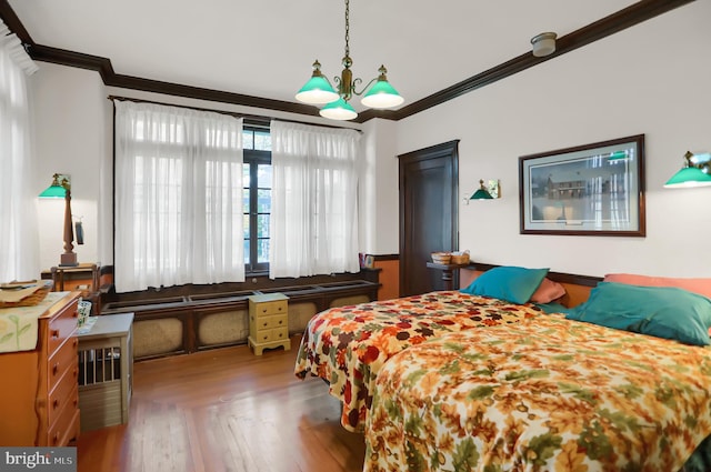 bedroom with ornamental molding, an inviting chandelier, and hardwood / wood-style floors