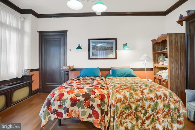bedroom with wood finished floors and crown molding