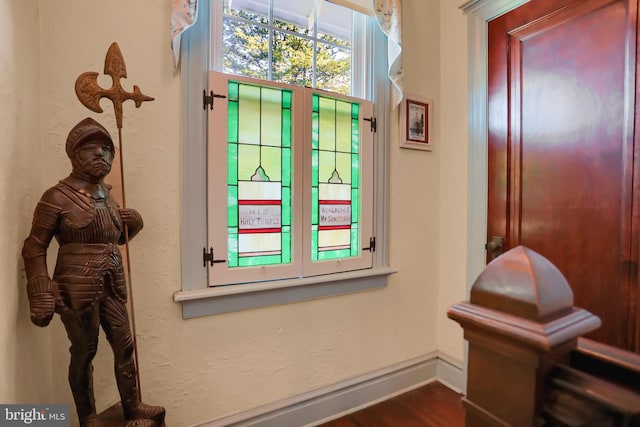doorway to outside featuring baseboards and dark wood-type flooring