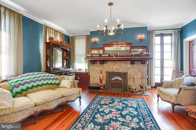 living room with an inviting chandelier, crown molding, hardwood / wood-style floors, and a fireplace