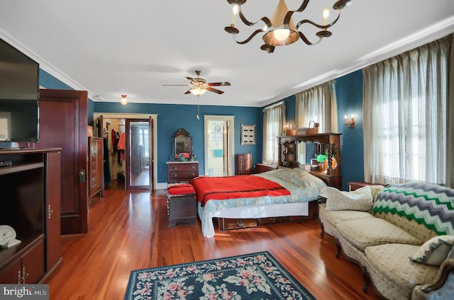 bedroom with crown molding, hardwood / wood-style floors, a closet, and ceiling fan with notable chandelier