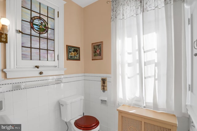 bathroom featuring radiator, toilet, wainscoting, and tile walls