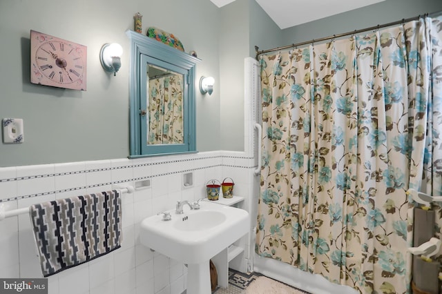 full bath featuring tile walls, shower / bath combination with curtain, and a sink