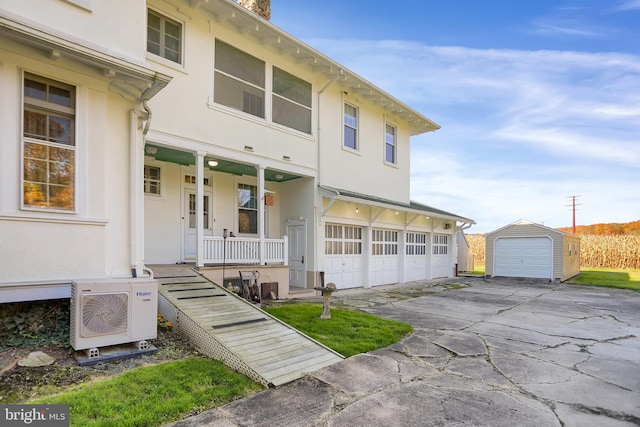 view of front facade with covered porch, ac unit, a garage, and an outdoor structure