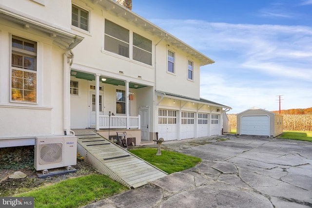 view of front of home with a porch, an outbuilding, driveway, ac unit, and stucco siding