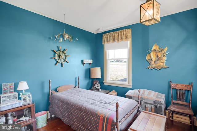 bedroom featuring wood finished floors, crown molding, and a chandelier