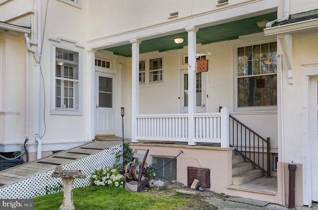 entrance to property with a porch and stucco siding