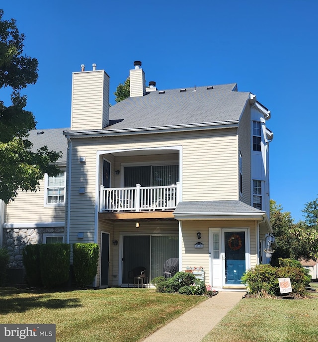 view of front of property featuring a balcony and a front yard