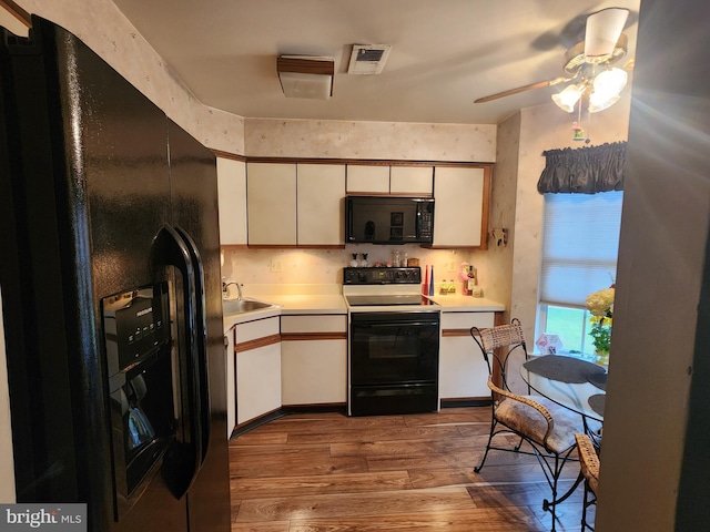 kitchen featuring black appliances, sink, ceiling fan, light wood-type flooring, and white cabinetry