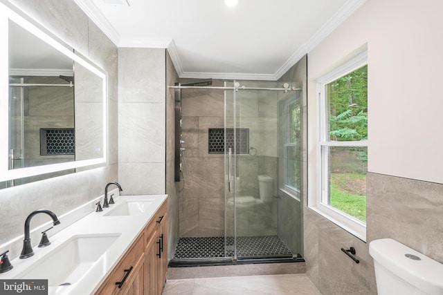 bathroom featuring a wealth of natural light, vanity, toilet, and tile walls