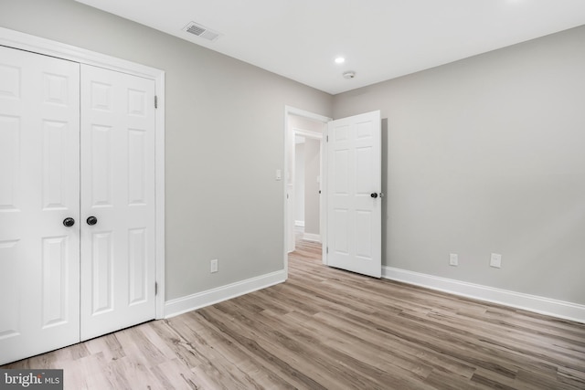 unfurnished bedroom with a closet and light hardwood / wood-style floors