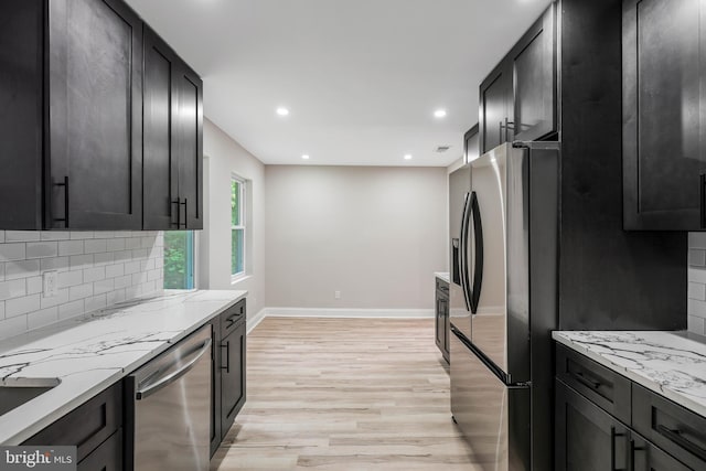 kitchen featuring light stone counters, stainless steel appliances, light hardwood / wood-style floors, and tasteful backsplash