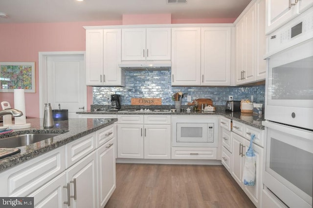 kitchen with white cabinets, white appliances, dark stone countertops, and sink